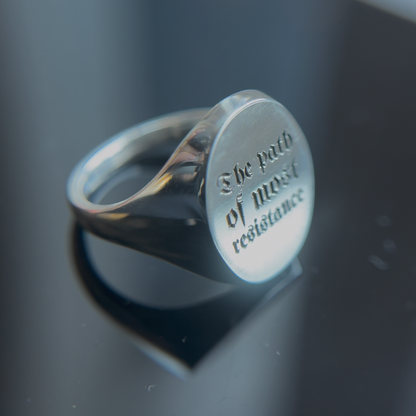 Silver ring with engraved text on a reflective surface